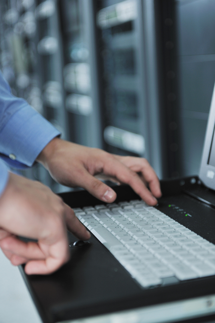 Homme qui écrit sur un clavier dans une salle de serveur de base de donnée pendant la réalisation d'une expertise Access